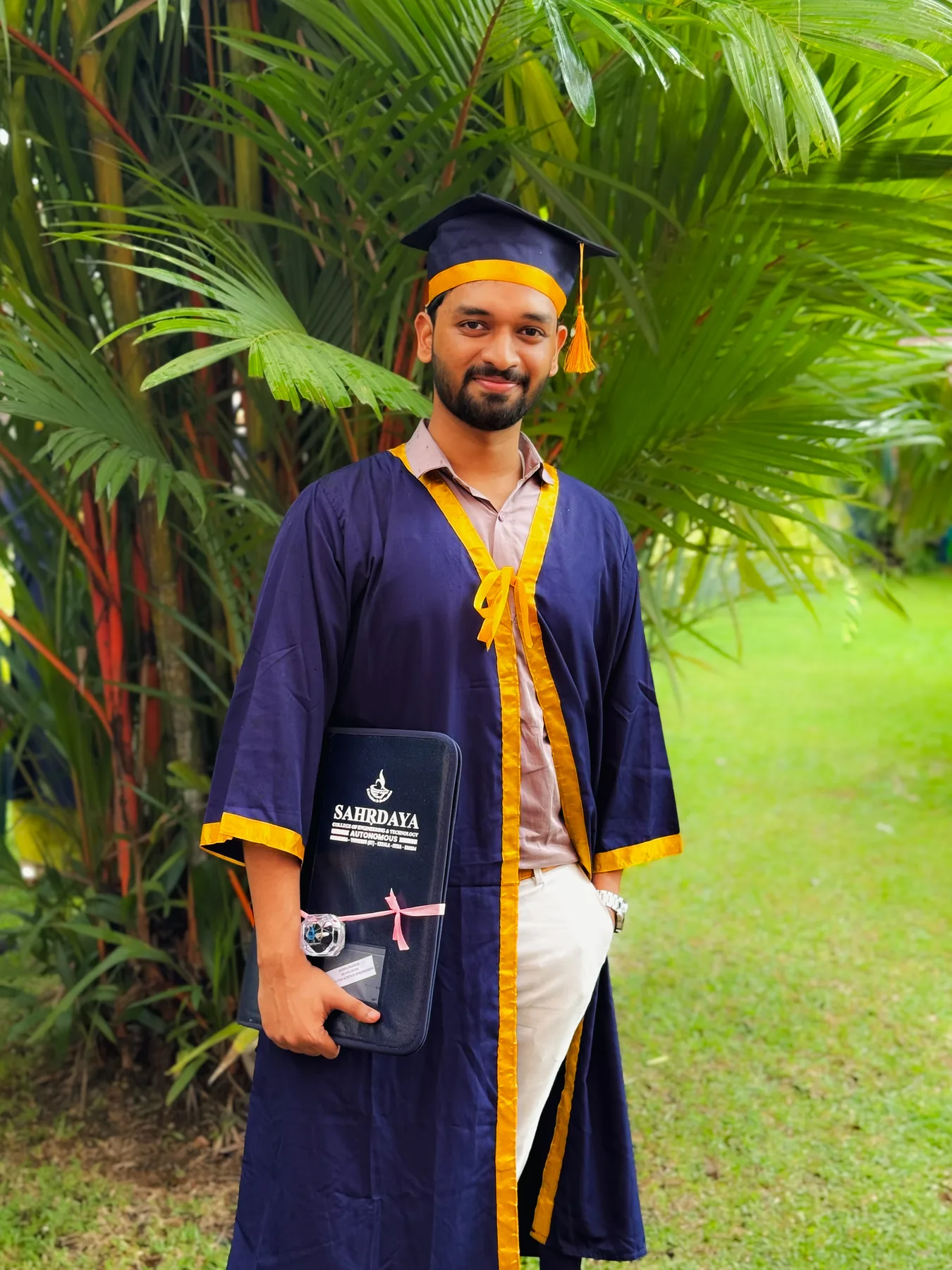 Robin Francis in graduation attire holding a Sahrdaya folder