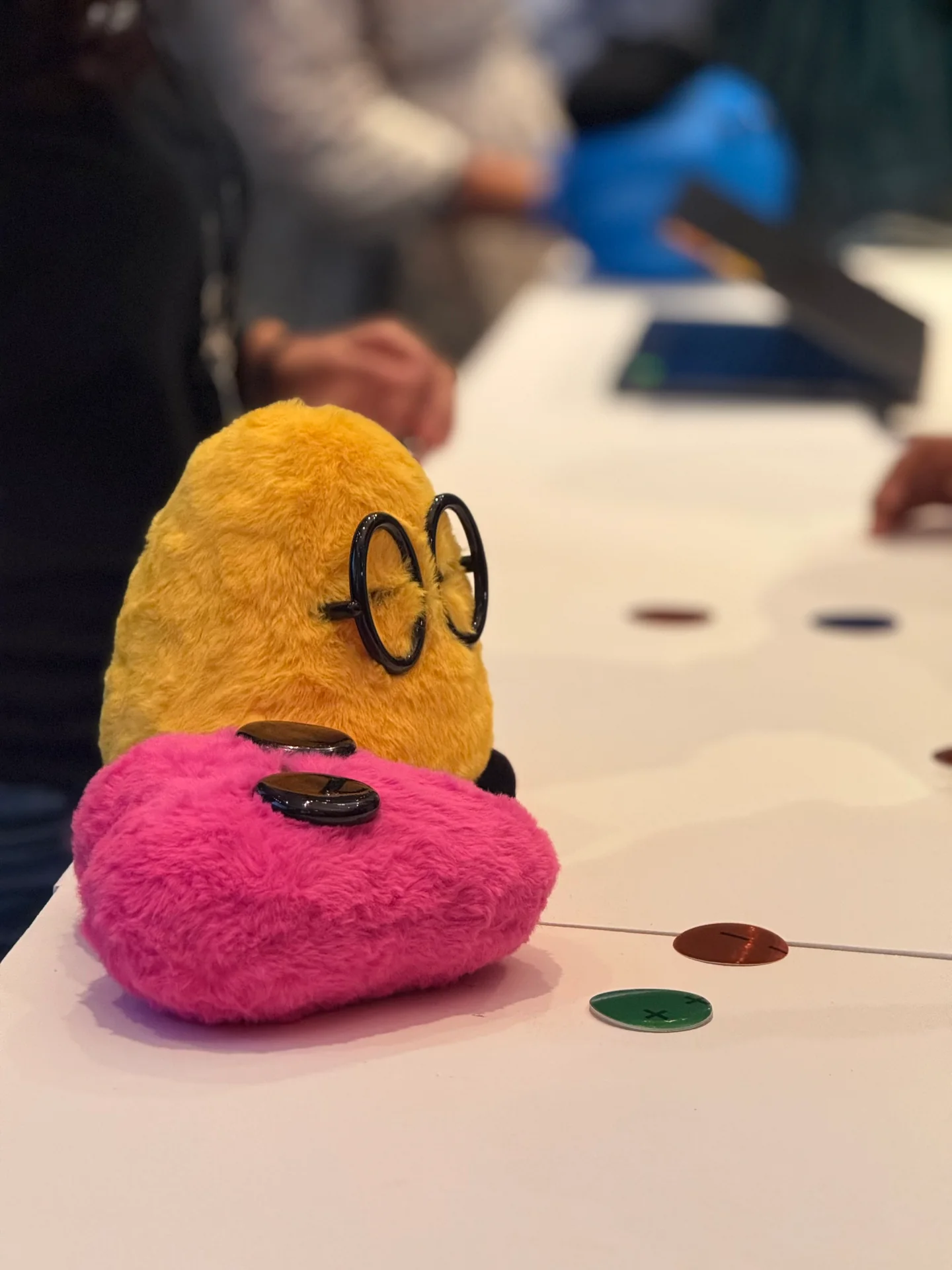 Yellow and pink OpenAI builder mascots on a table at the DevDay Exchange attended by Robin Francis